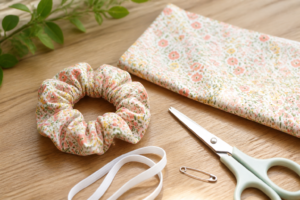 Chouchou en tissu fini à côté d'un rectangle de tissu, élastique et épingle à nourrice